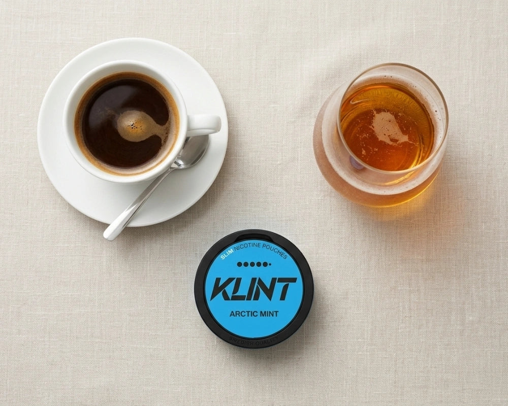 Tazza di espresso, un bicchiere di whisky e una bustina di nicotina KLINT Arctic Mist visti dall'alto