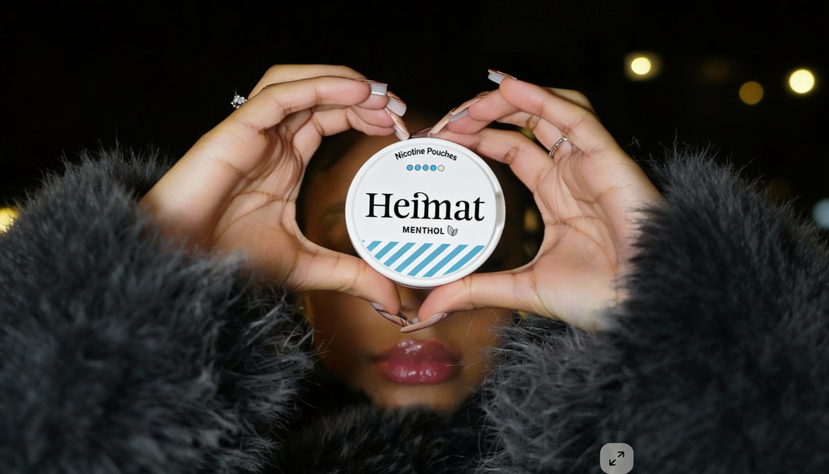 Custodia di Heimat Menthol Nicotine Pouches a forma di cuore in mano, foto lifestyle con donna in cappotto nero